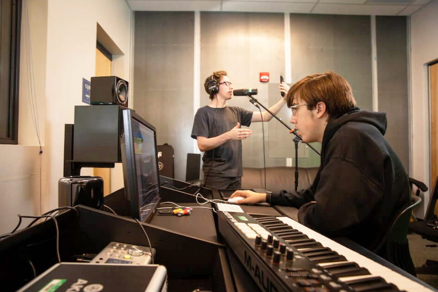 Students working on computer and on a microphone