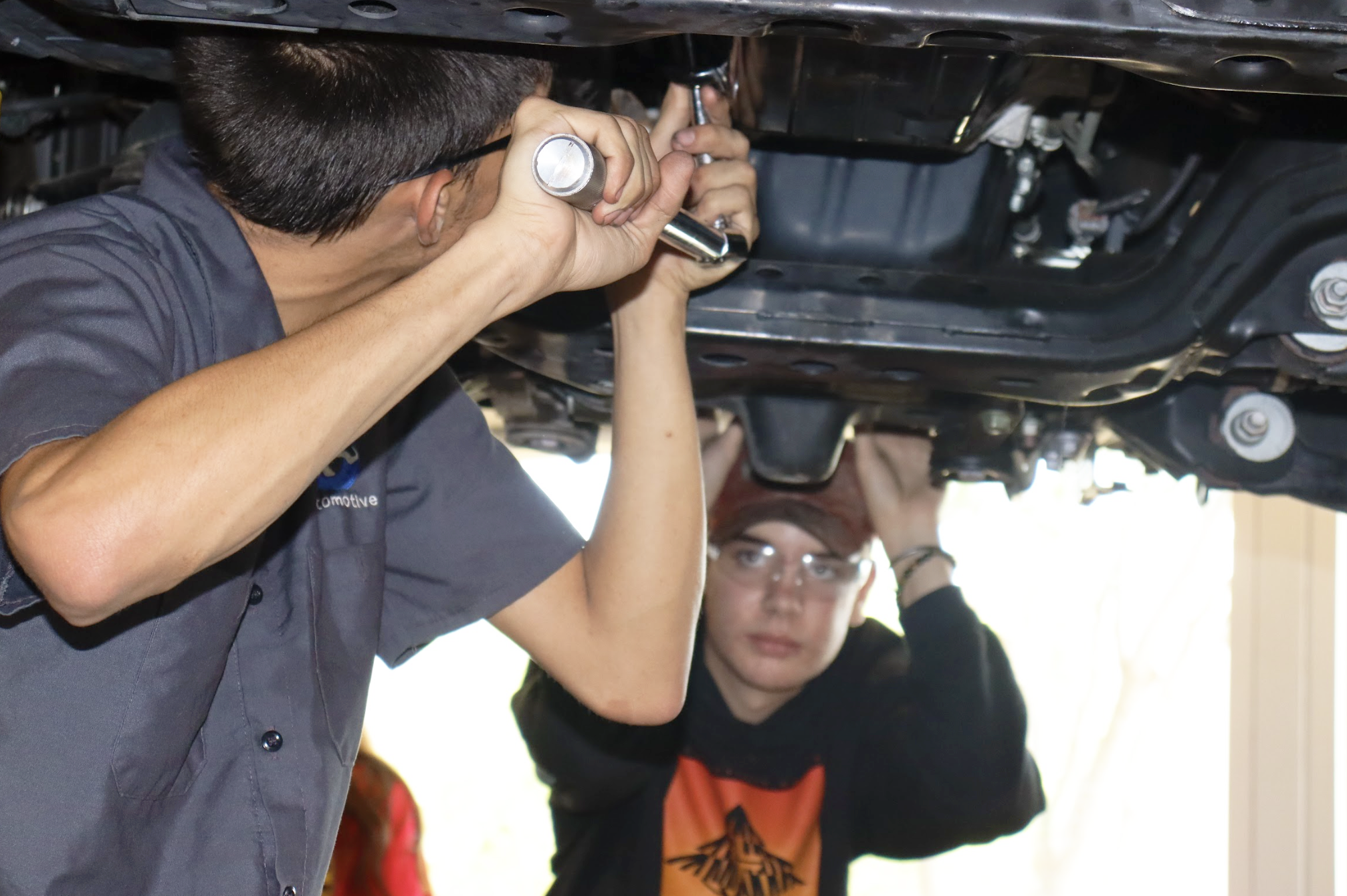 Teacher and student working under a car