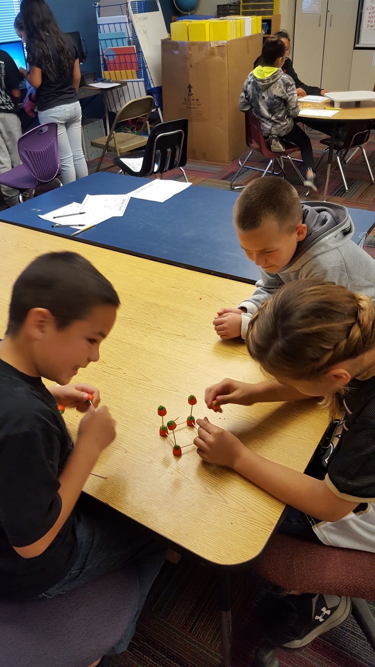 Kids connecting candy with toothpicks to make a tower