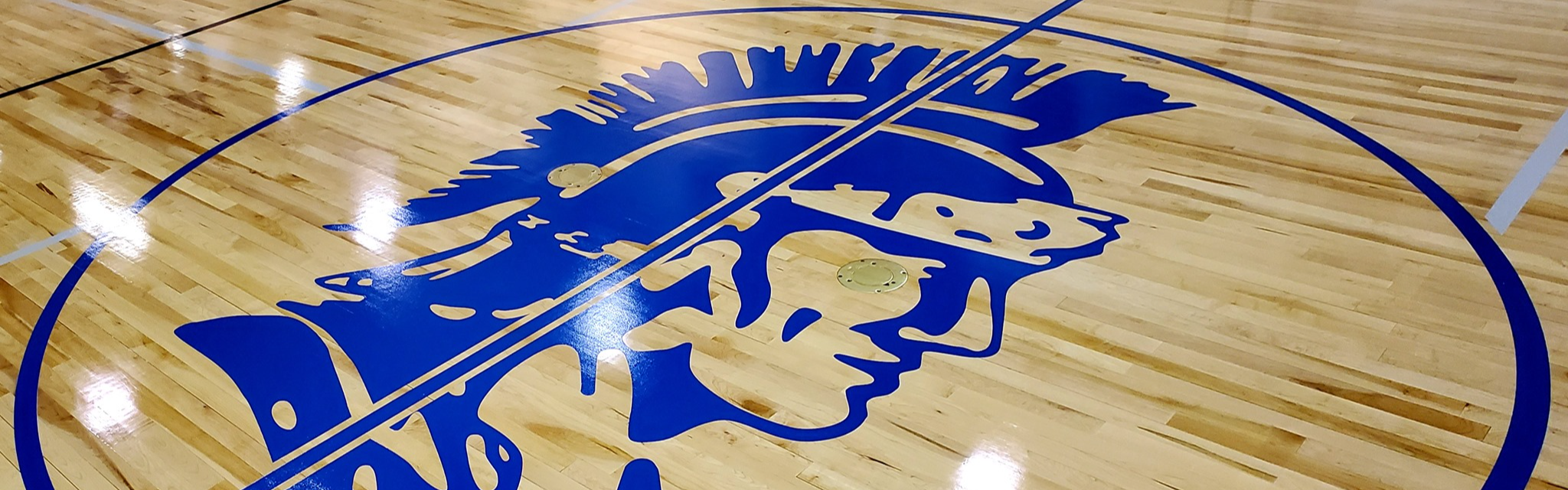 A picture of the gym floor with the Trojan logo in blue