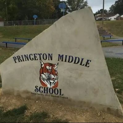 A large, stone sign displays "Princeton Middle School" with a tiger emblem. Behind the sign are benches and a grassy area.