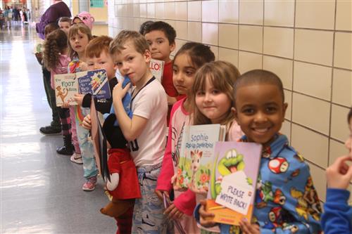 Young students standing in a line holding books