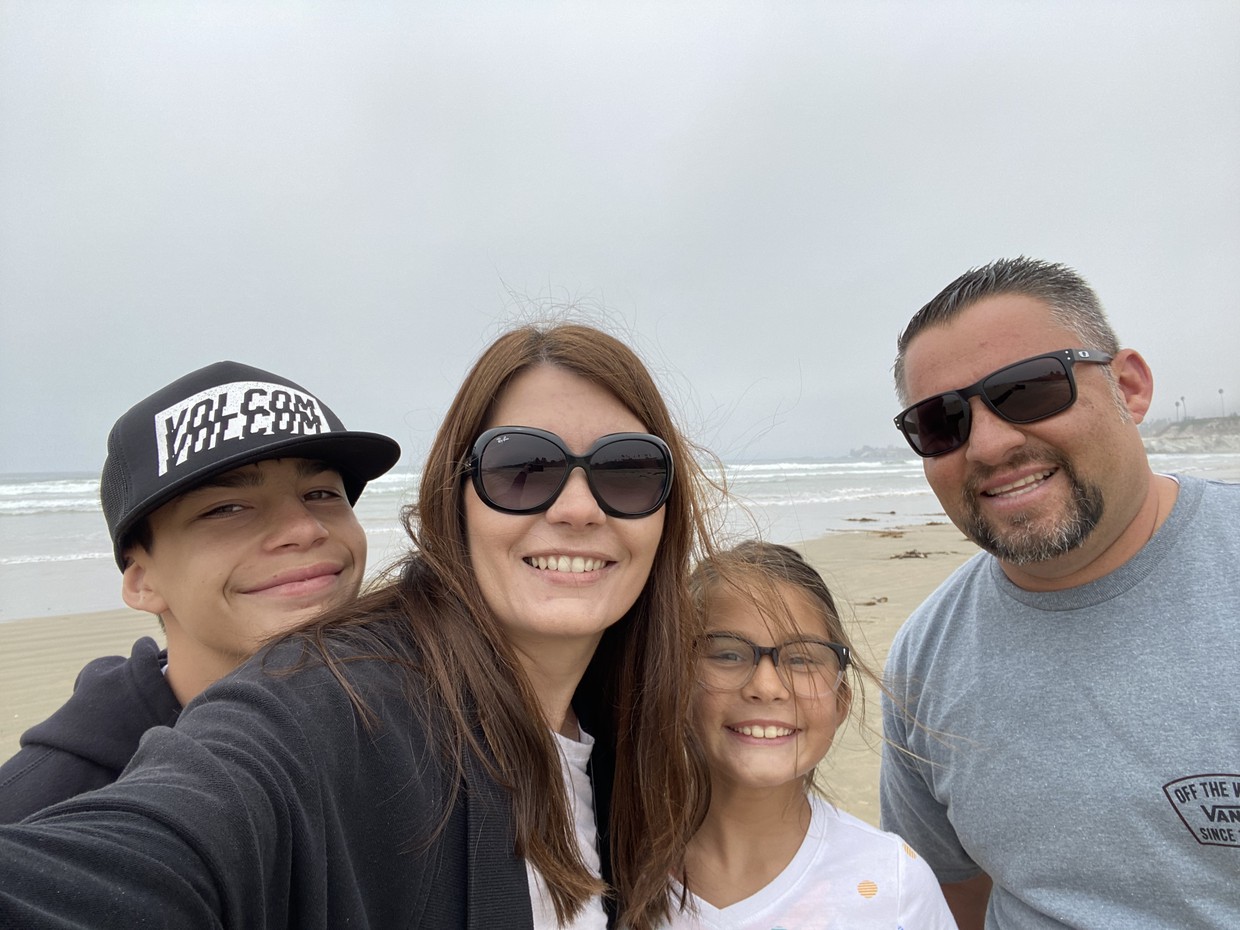 Mrs. Chavez in sunglasses in front of the ocean, smiling with her family
