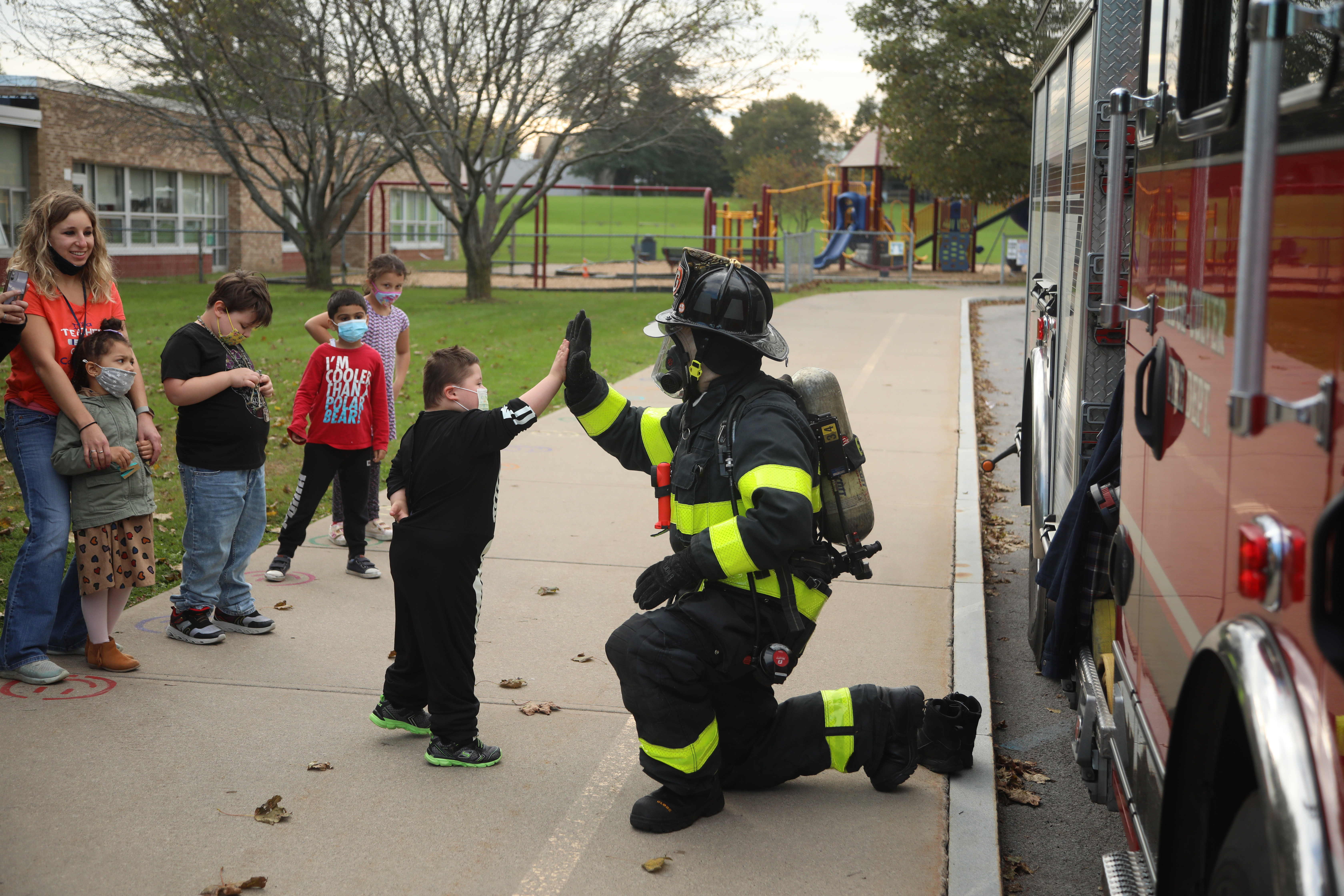 student high fiving a fire fighter