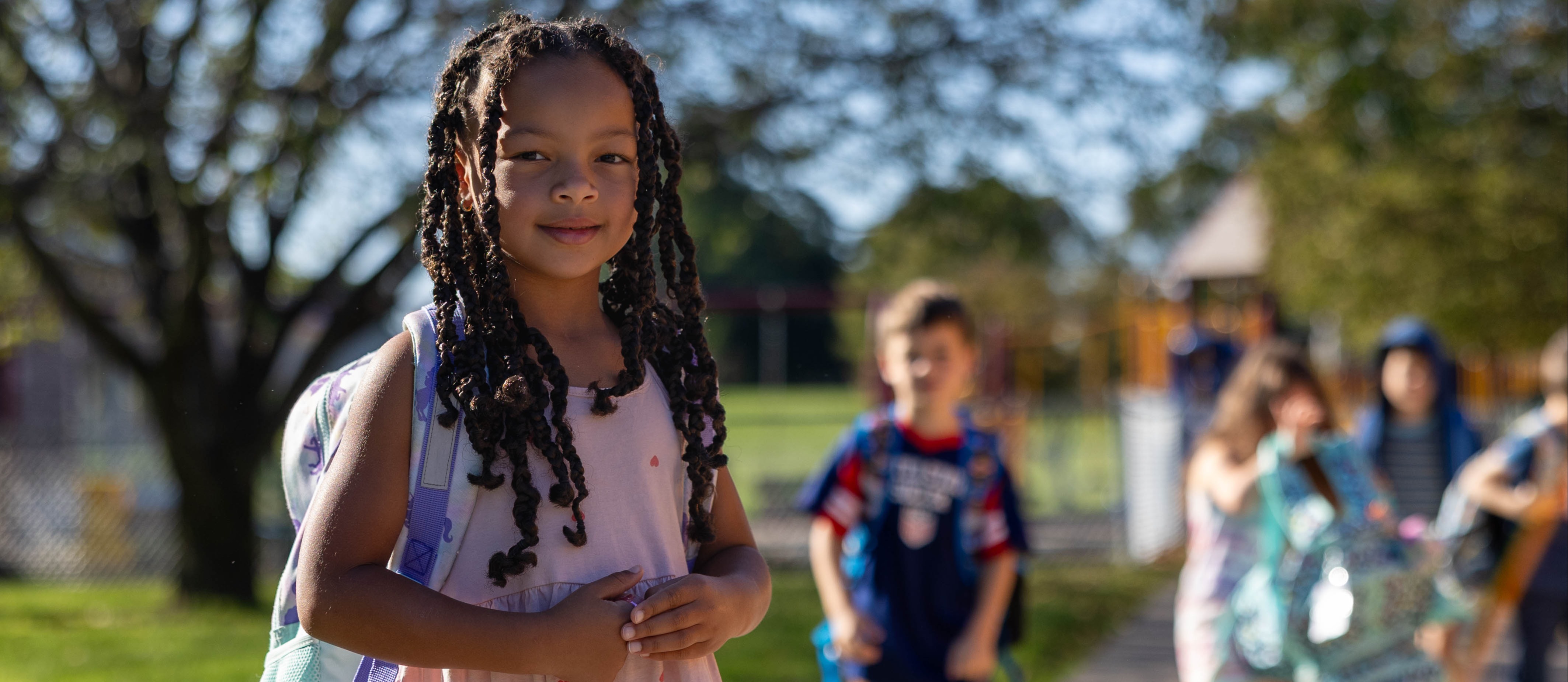 student smiles and walks into school with backpack