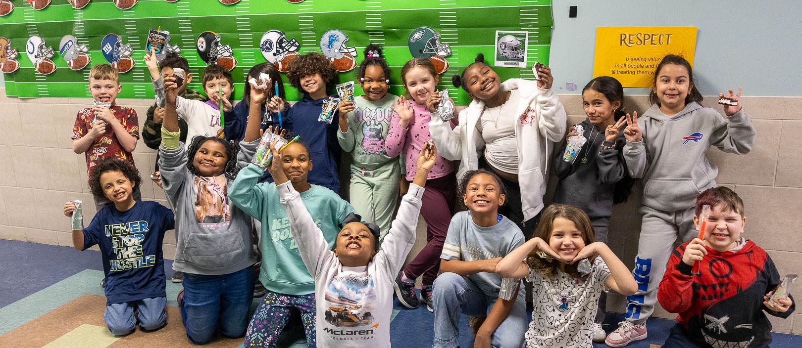 Class poses for a photo in front of football bulletin board for having best attendance