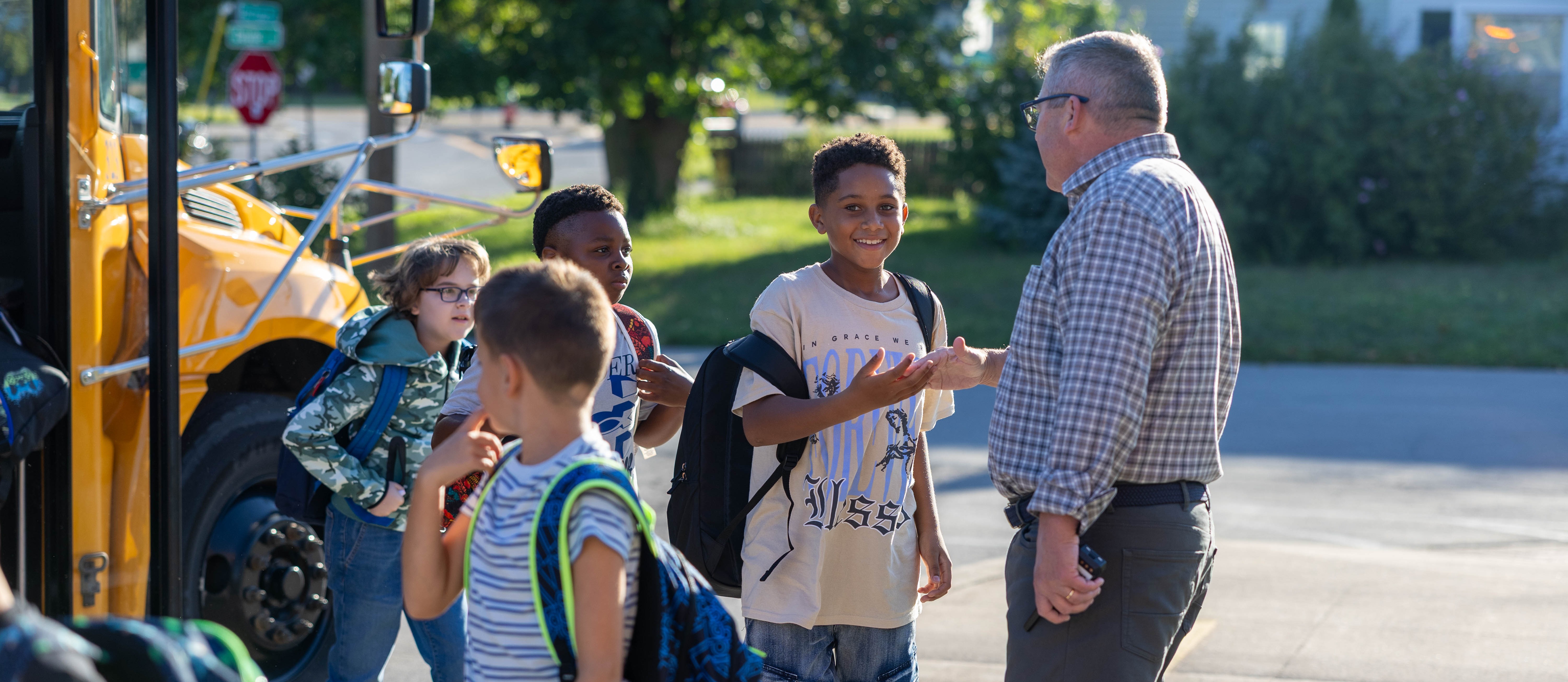 students high five principal after getting off of the bus