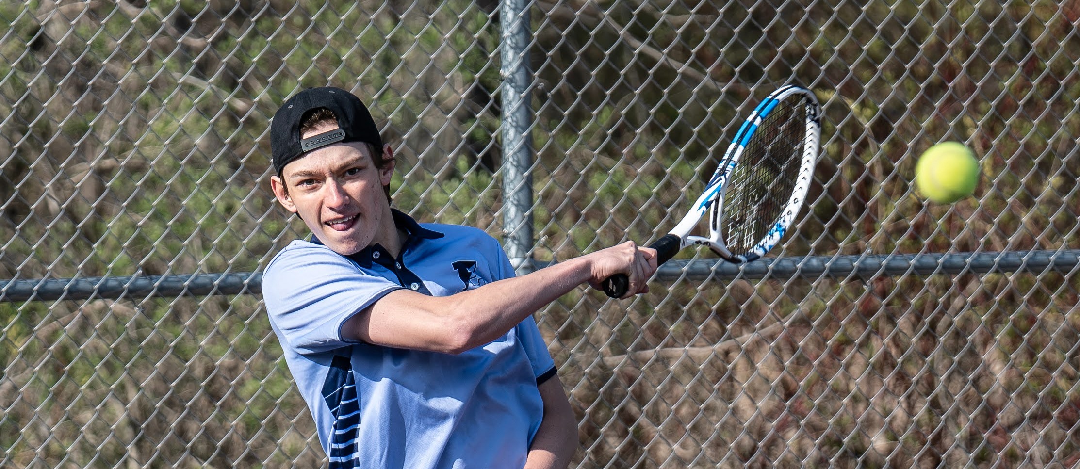 Student prepares to hit tennis ball with racket 