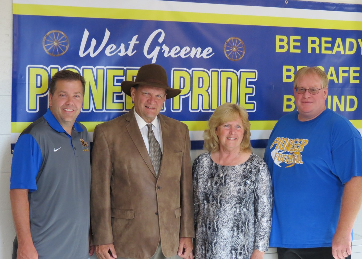 photo of adults standing in front of a west greene sign