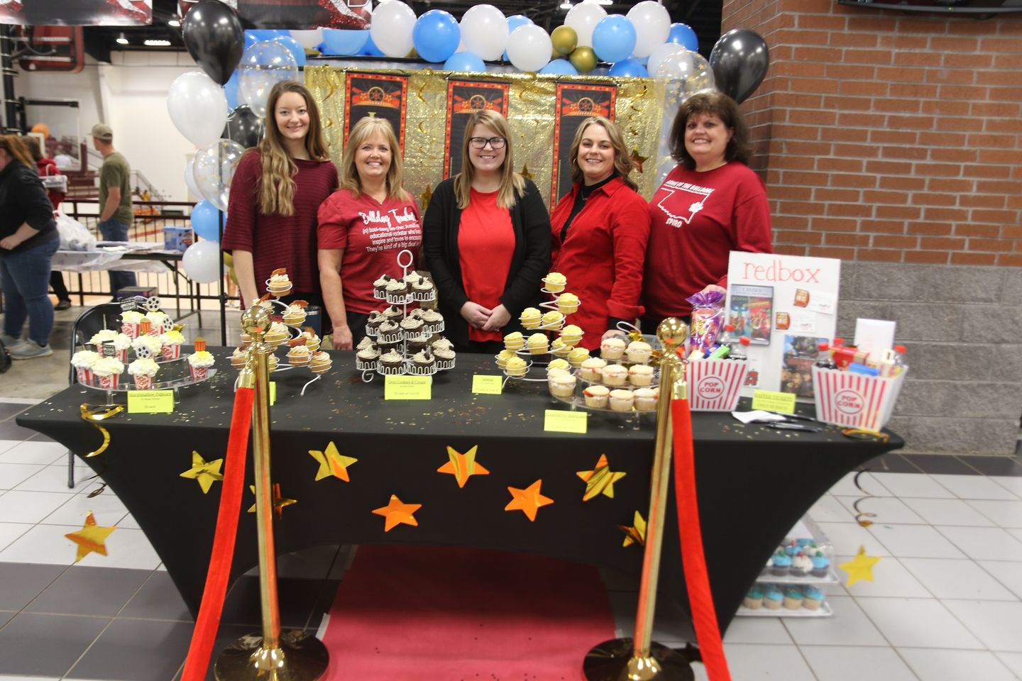 Staff members stand behind a table with desserts and streamers