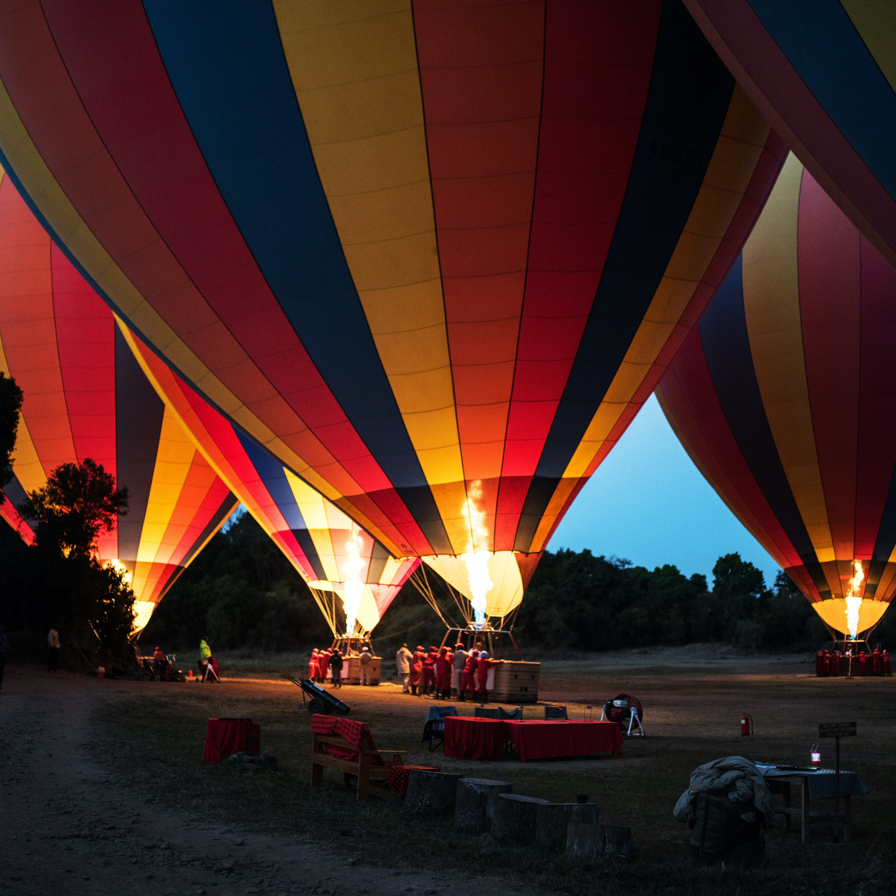 4 multicolored hot air balloons being lit at night