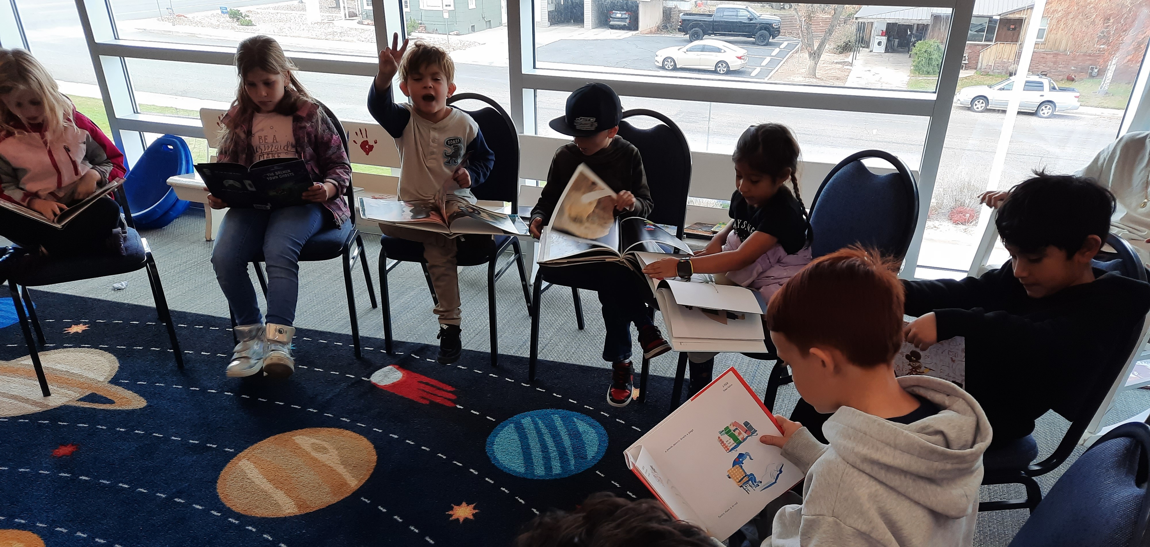 Second grade students evaluate books in the library.