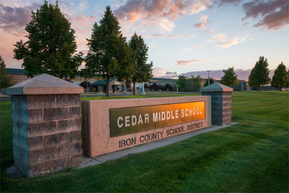sign that says cedar middle school with a sunset reflecting on it