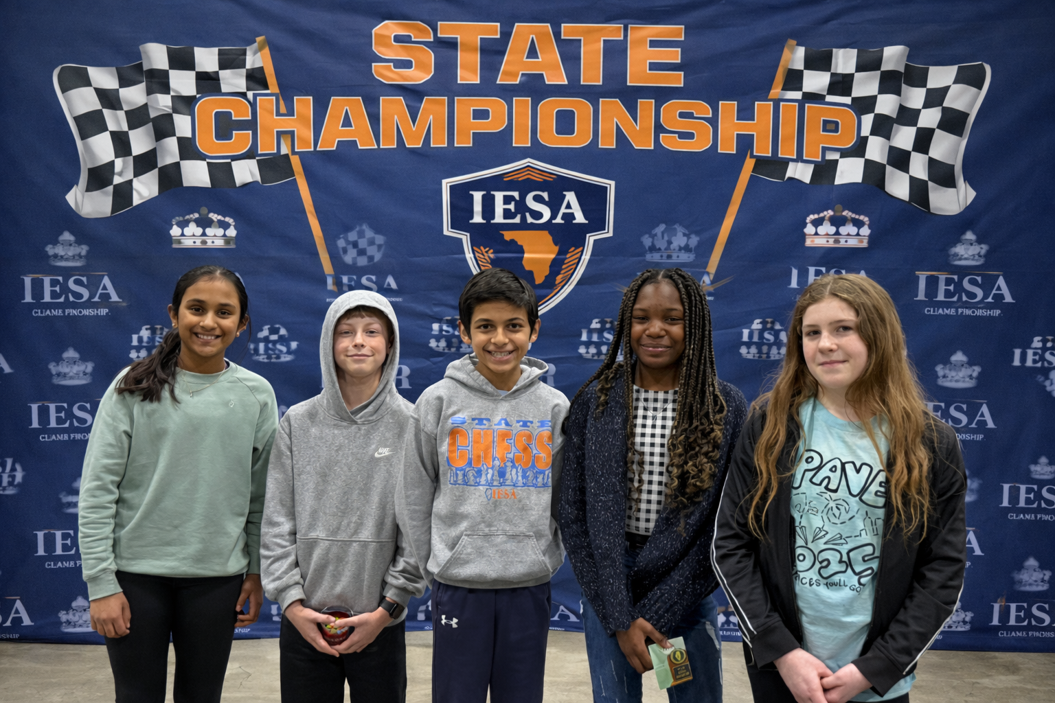 Five children stand in front of a blue banner reading "State Championship" with checkered flags.