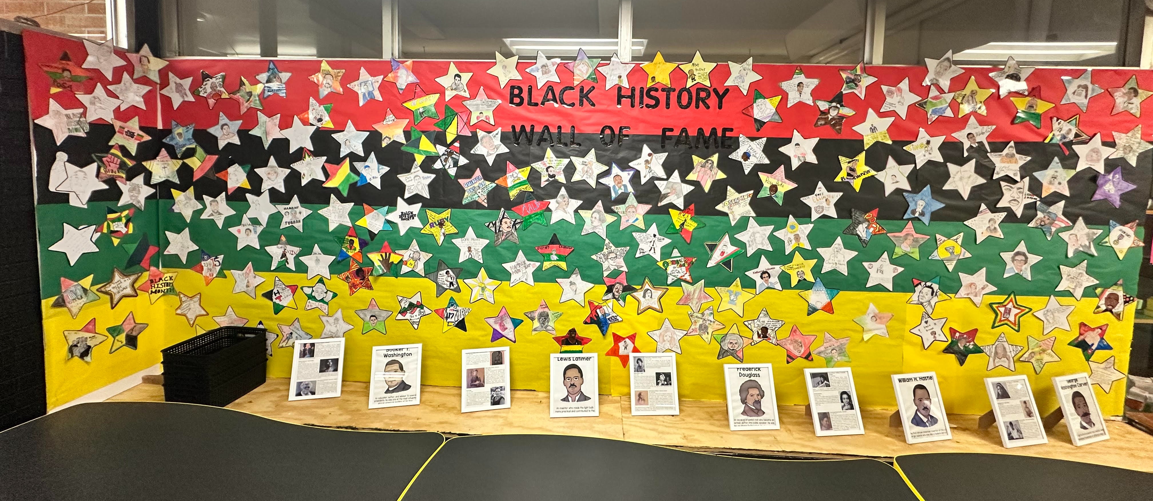 A wall decorated with black, red, and green colors. Stars and images of individuals are featured. Banner reads "BLACK HISTORY."