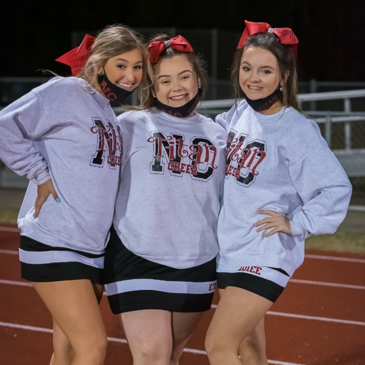 Three cheerleaders posing for a picture on the track