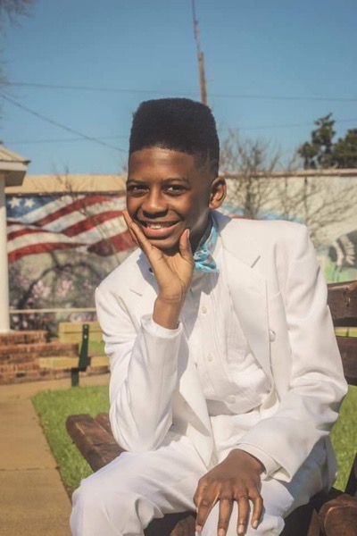 Male student in a white tux posing for a photo