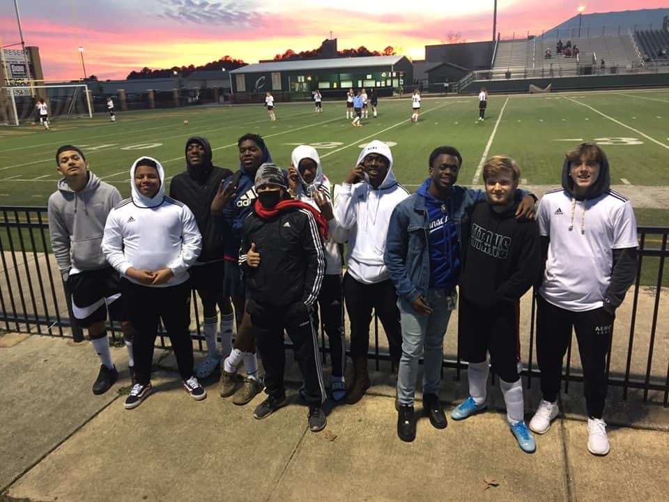 A group of students posing for picture in front of the football field