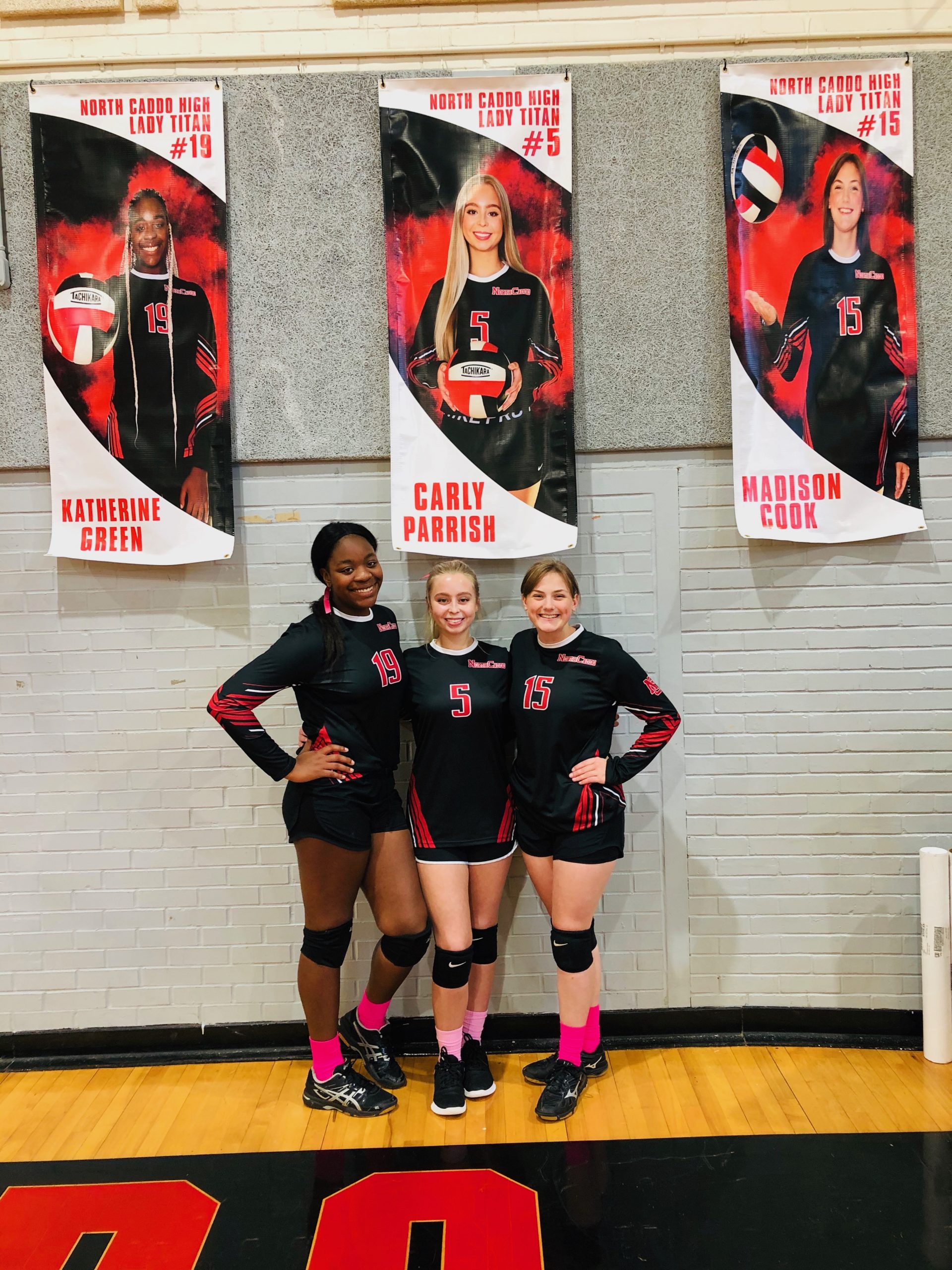 3 athletic students posing under record banners with their pictures