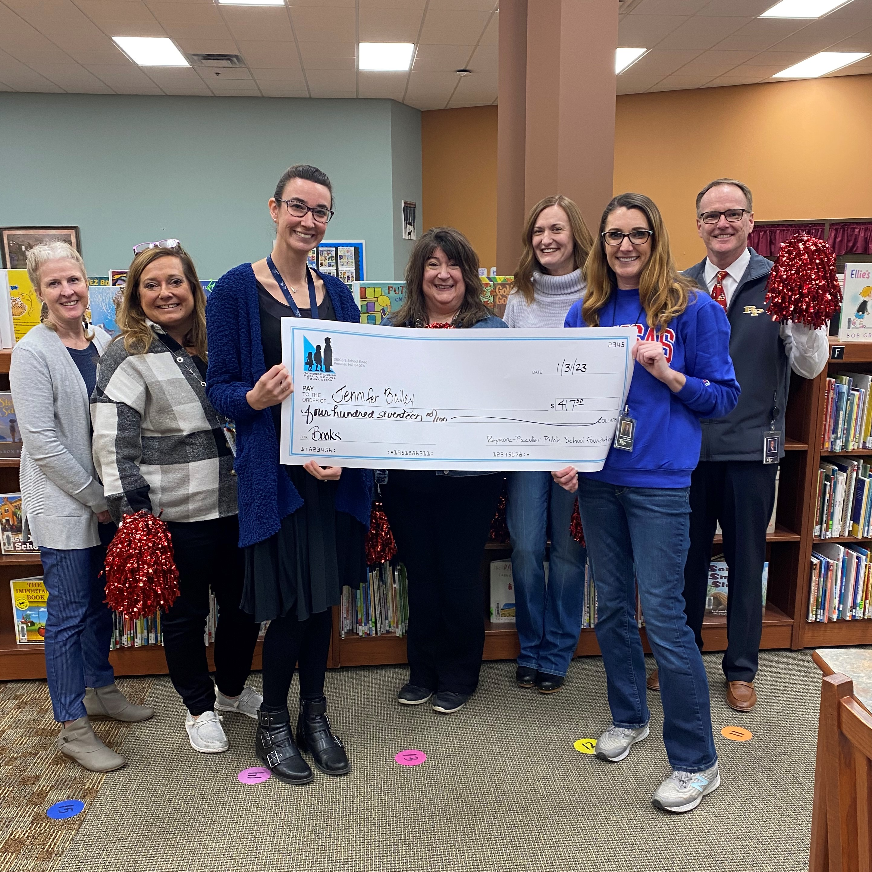 Bridle Ridge Librarian Jen Bailey holds a giant check
