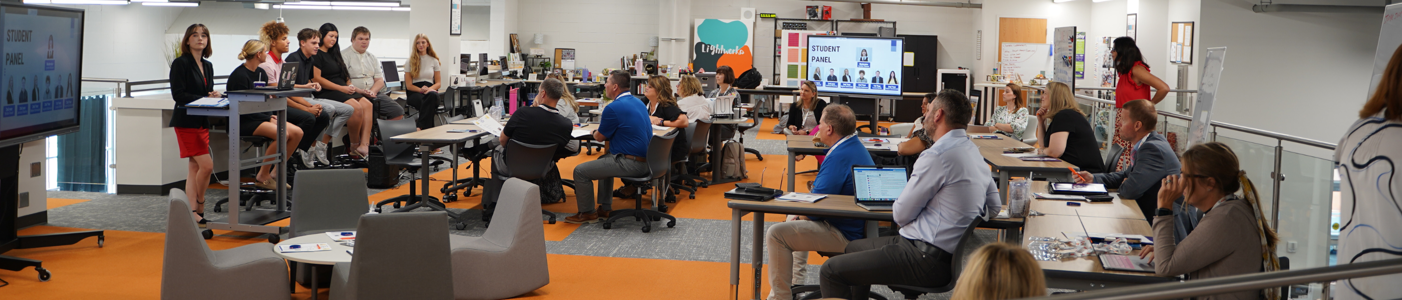 A group of people sitting together in an open room listening to a discussion panel