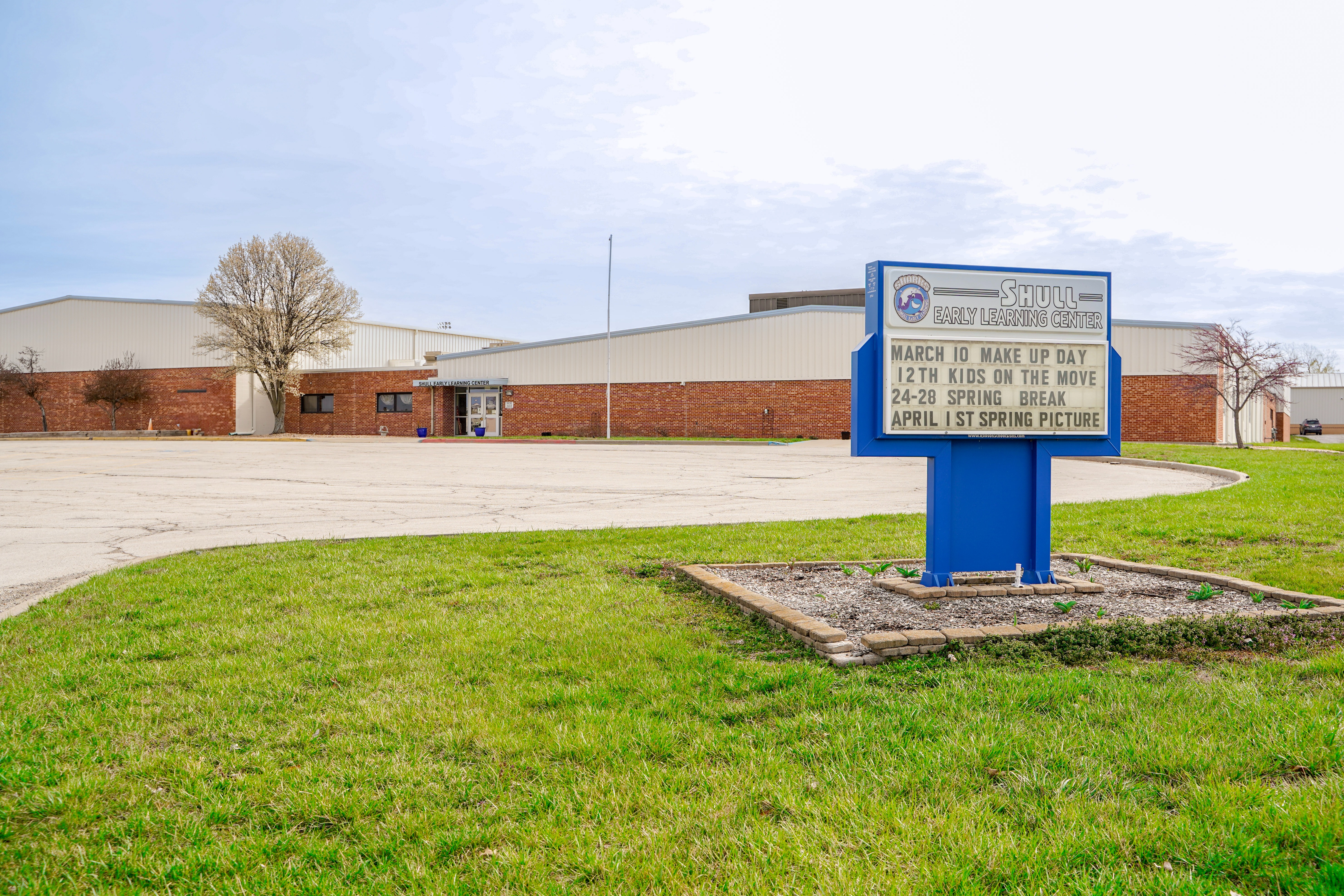 The exterior of a brick school building with a sign in the foreground that reads, "Shull Early Learning Center."