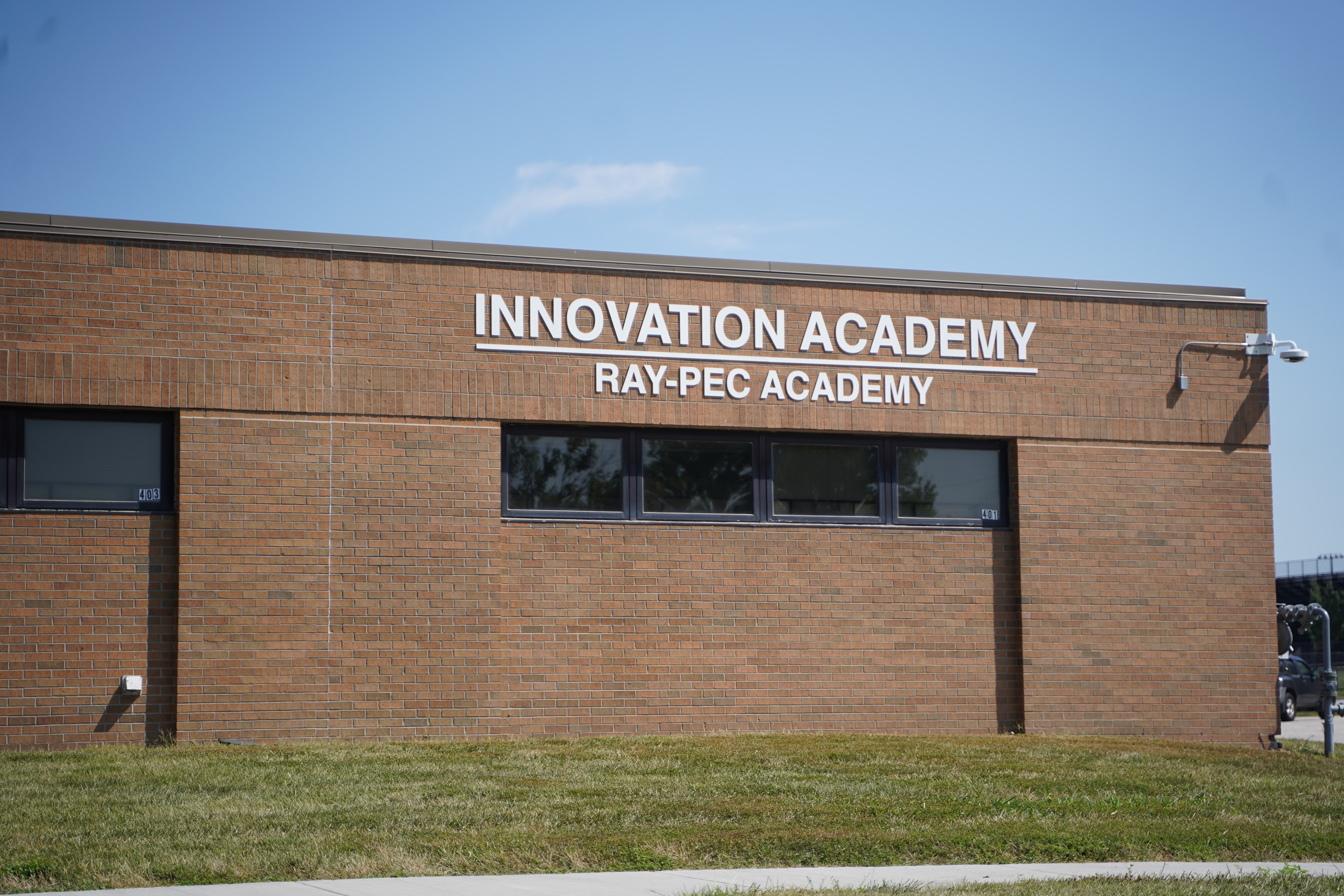 A brick school building with words on the side that read, "Innovation Academy Ray-Pec Academy"