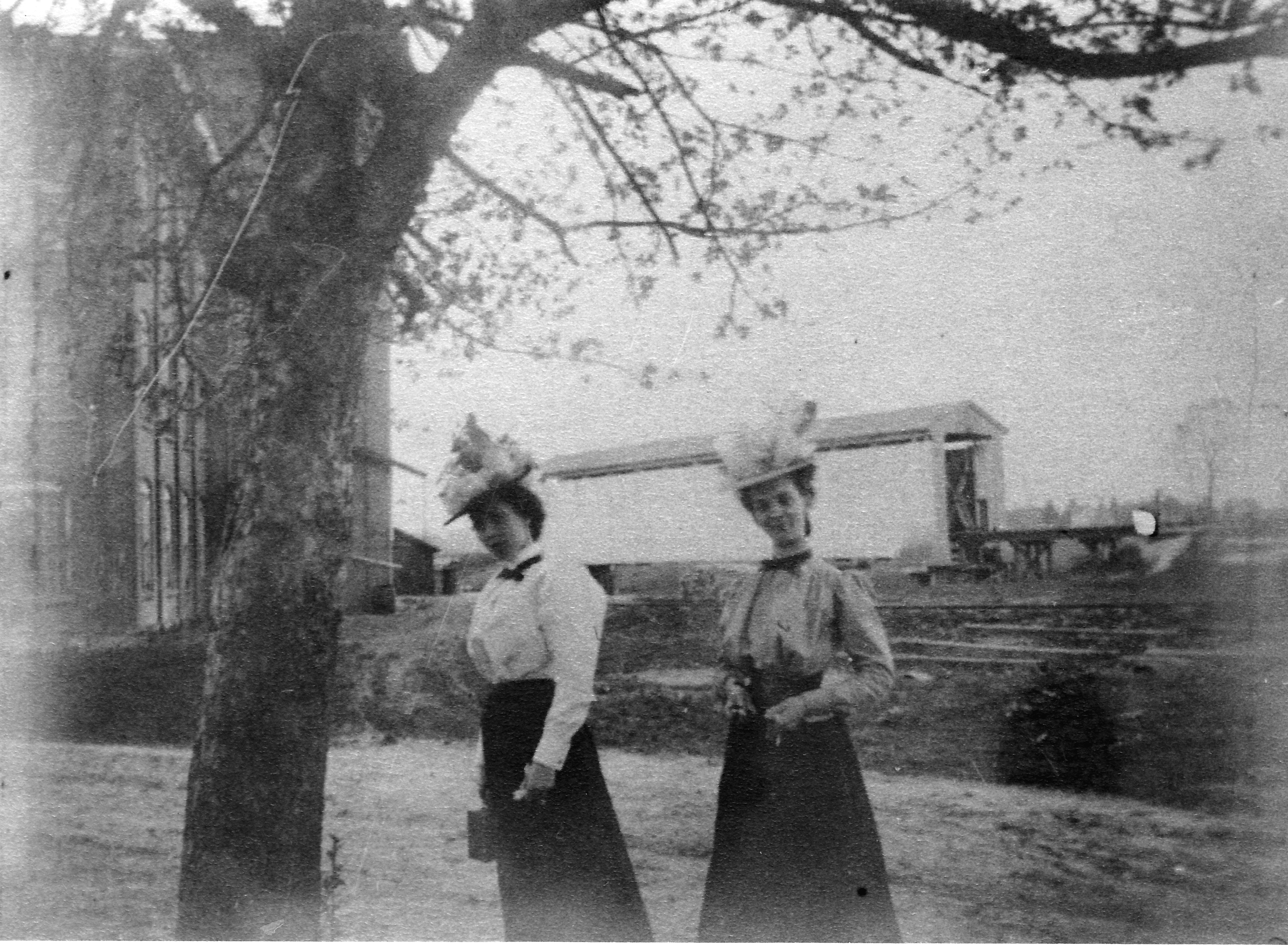 Carrie and Ida Murfitt at corner of West Congress and Mill Street.  Kellogg & Buck Flour Mill to left rear.  Covered railroad bridge of L.S. & M.S. Railway over Bean Creek (Tiffin River) prior to July 1908.