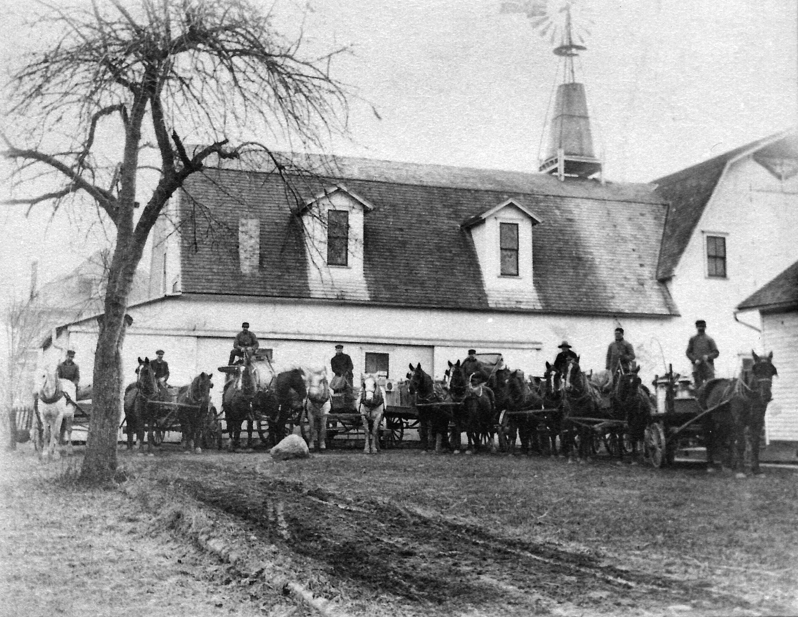 Baldwin Trucking Company.  Barn with teams stood back of present day 116 E. Locust St.  Photo of 1911 or 1912.  Delbert Badlwin (owner), Will Clapp, Frank Bailey, Elmer Milliman, Charles Bauman, Jonas Henry, George Hoadley, Wesley Swaney.