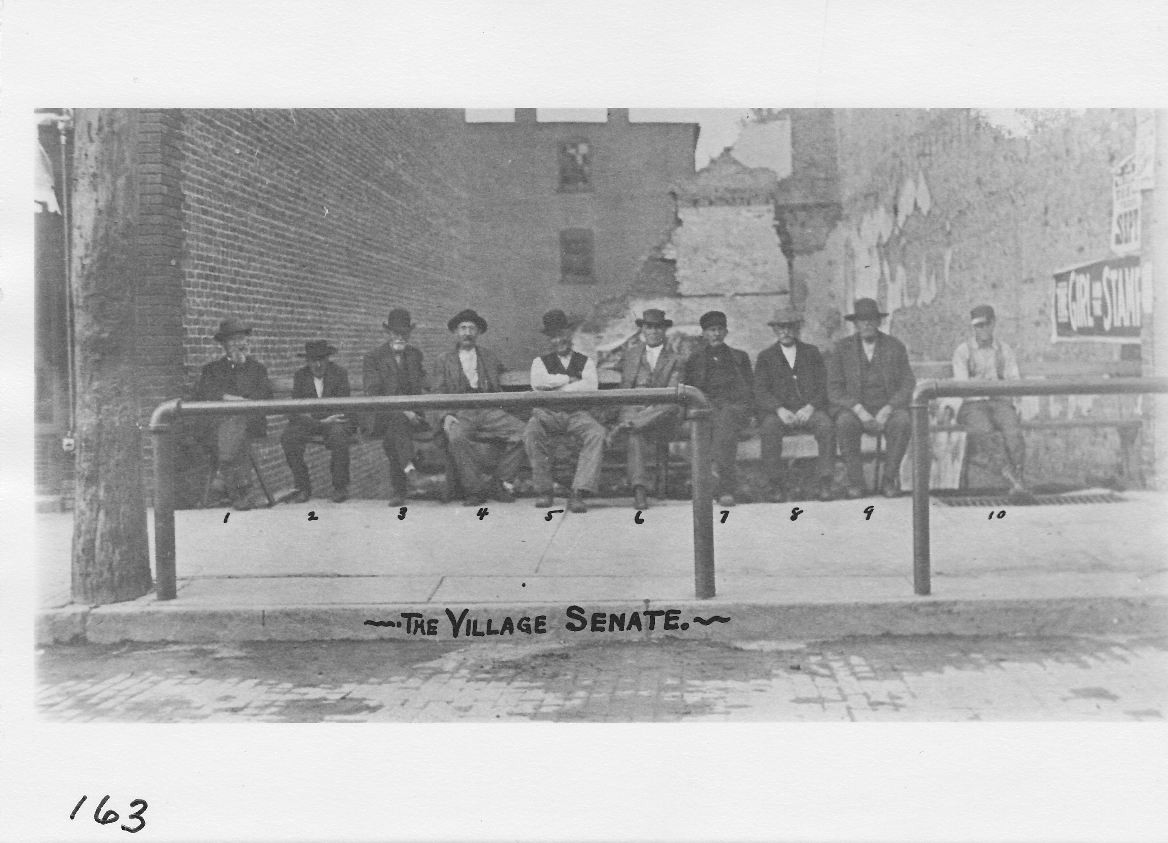 The “Village Senate, the same location as a previous photo but with some new faces.  Extreme left – Civil War veteran John Hanna, 3rd from left – Civil War veteran Bill Price, 6th from left – Sam Humphrey, retired merchant. Open area was just west of Allen Jewelry store. Photo about 1914.