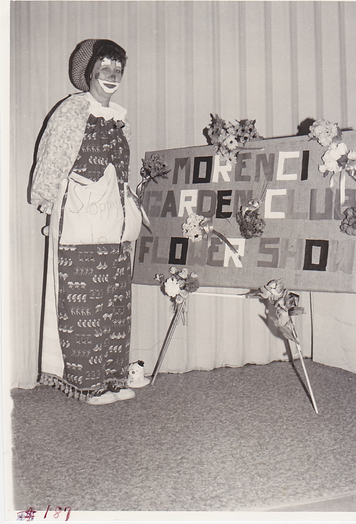 Dressed in one of her many clown makeups, Joyce Woerner, a member of the Morenci Garden Club, pays a visit to the club’s flower show during Festival Days of 1980.