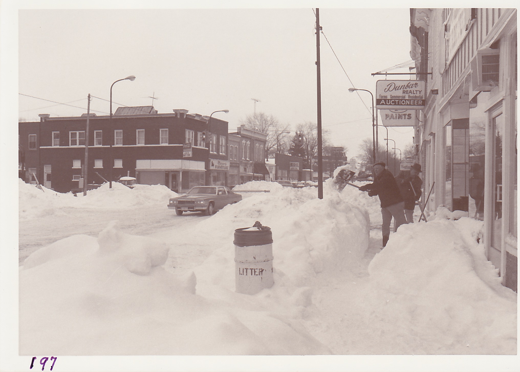 Harold Smith and Mel Oberling shoveling a path in front of their respective businesses, following the blizzard.