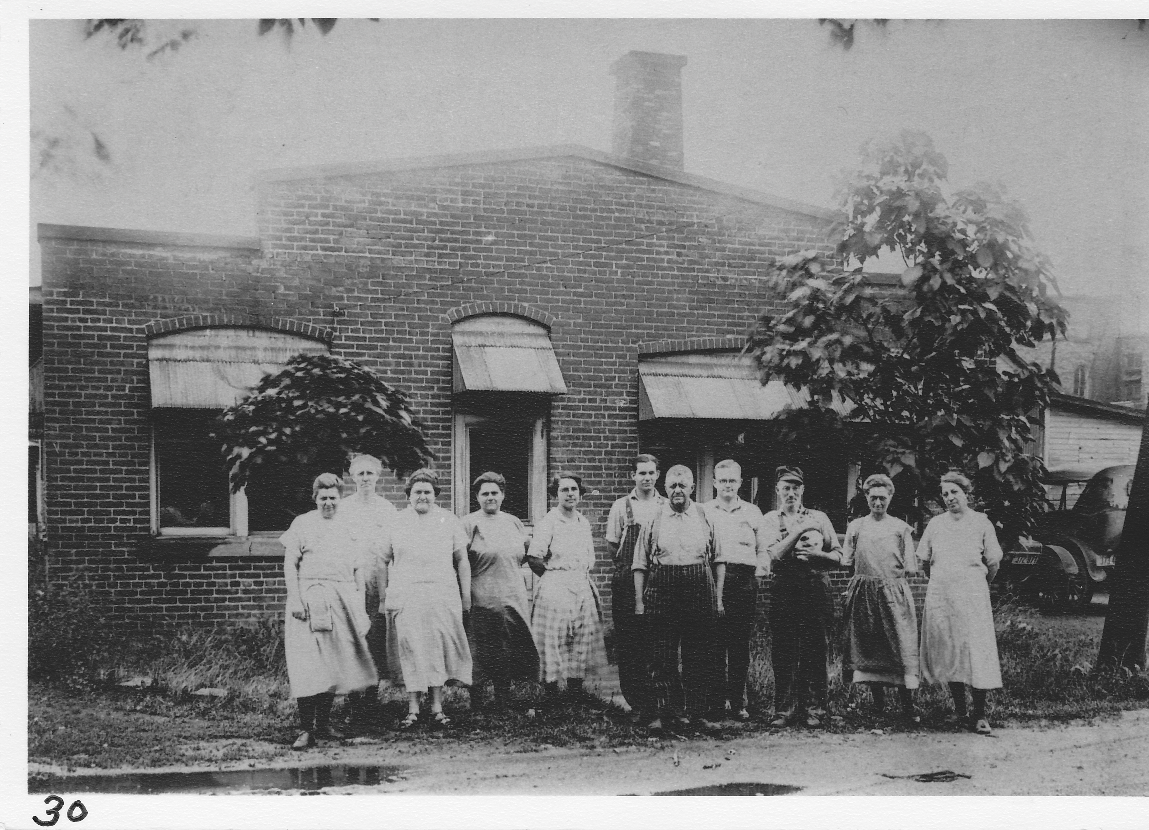 Scofield Casket Mfg. Company and employees – now city parking area on Baker Street. Iva Helms, Bess Deyo,  L. Tuttle, Lydia Rock, Dora Shaffer, Max Smith, Pete Hause,  E. Schofield, Jap Gephart (with Tilley the cat), Rose Koon, Artie Siders.