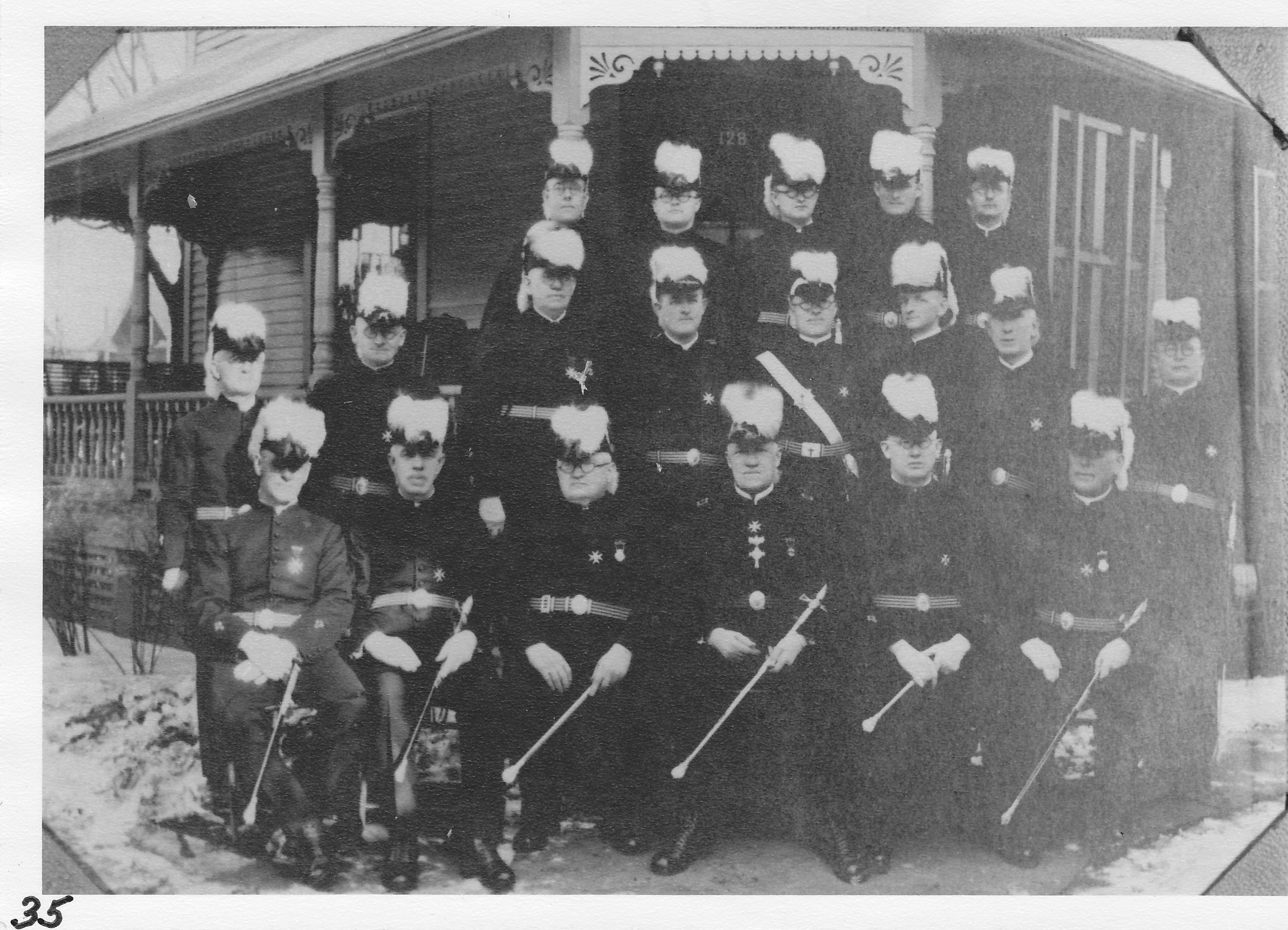 Knights Templar, Adrian Commandary, sitting on front porch steps of  Dr. C. A. Blair’s house at 128 North St.  Members from Morenci,  Top row (l-r) Hoig Gay, Ernest Schofield, ______________, ______________, ______________. Center row (l-r) ______________, Milan Smith, E. B. Butler, Wm. Ackland, ______________, Claude Lee, Harry Allen.   Front row (l-r) ______________, Dr. Older, Dr. Charles Blair, ______________, Ira Metcalf, Winfied Scott.