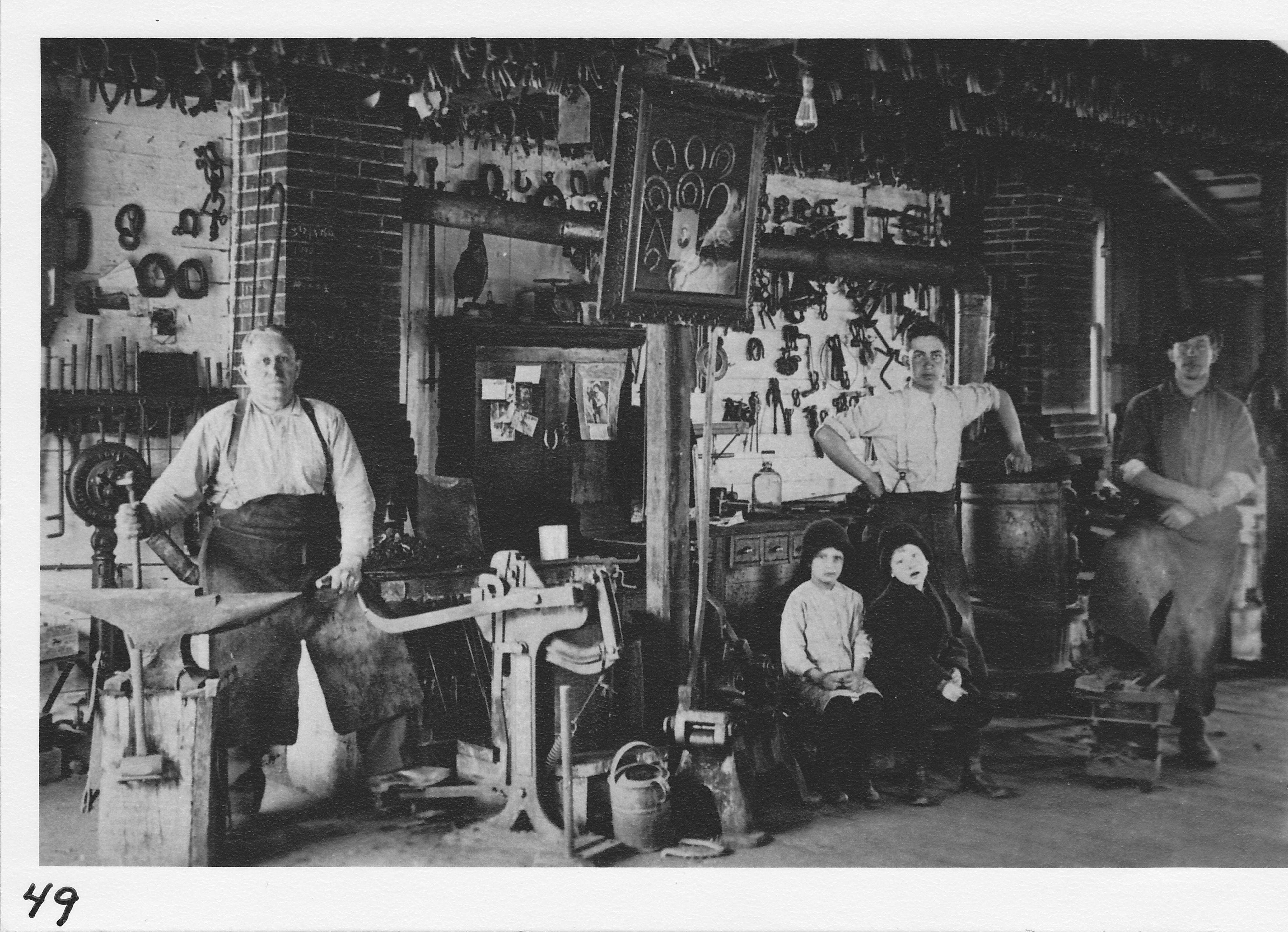 Pete Stetten’s Blacksmith Shop at  turn of century, located on Baker St.  Pete seated at left.