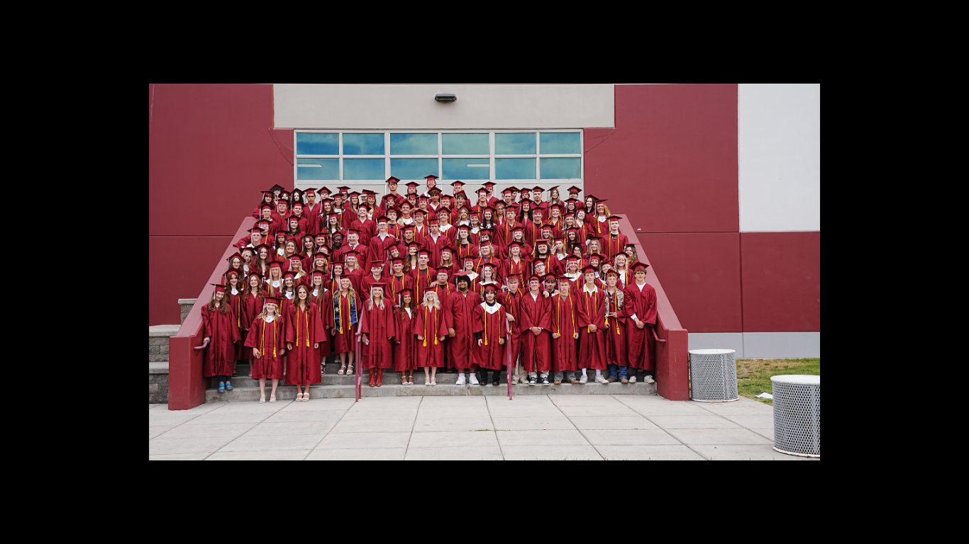 the graduating class of 2026 posing in their red caps &amp; gowns on the steps in front of hamilton high school