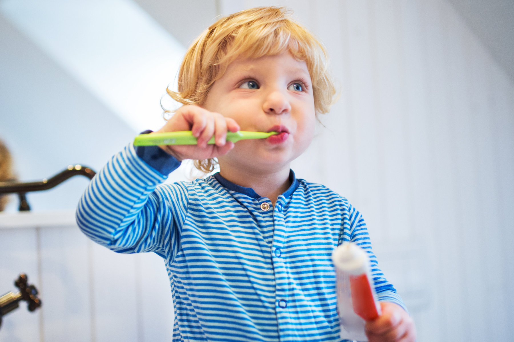 toddler in blue brushing teeth