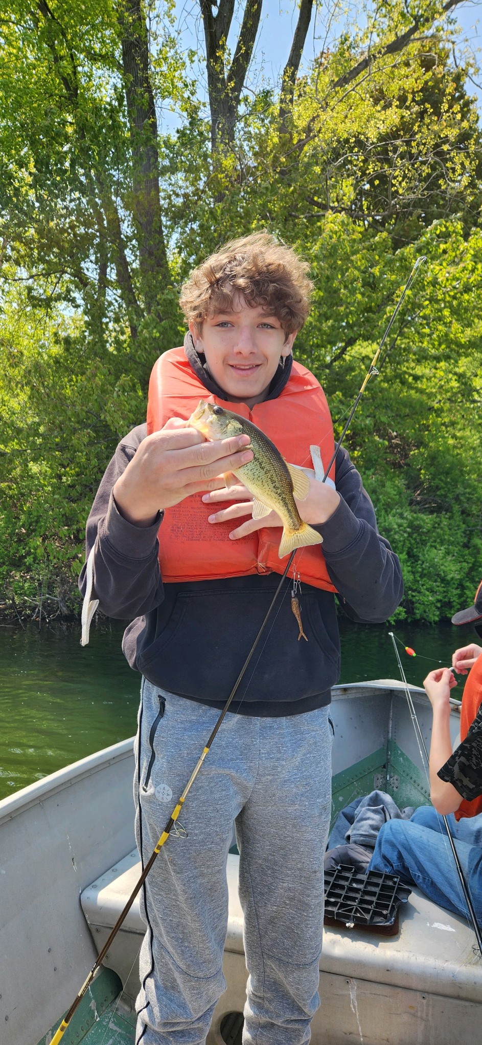 Student in life jacket holds fish they caught.