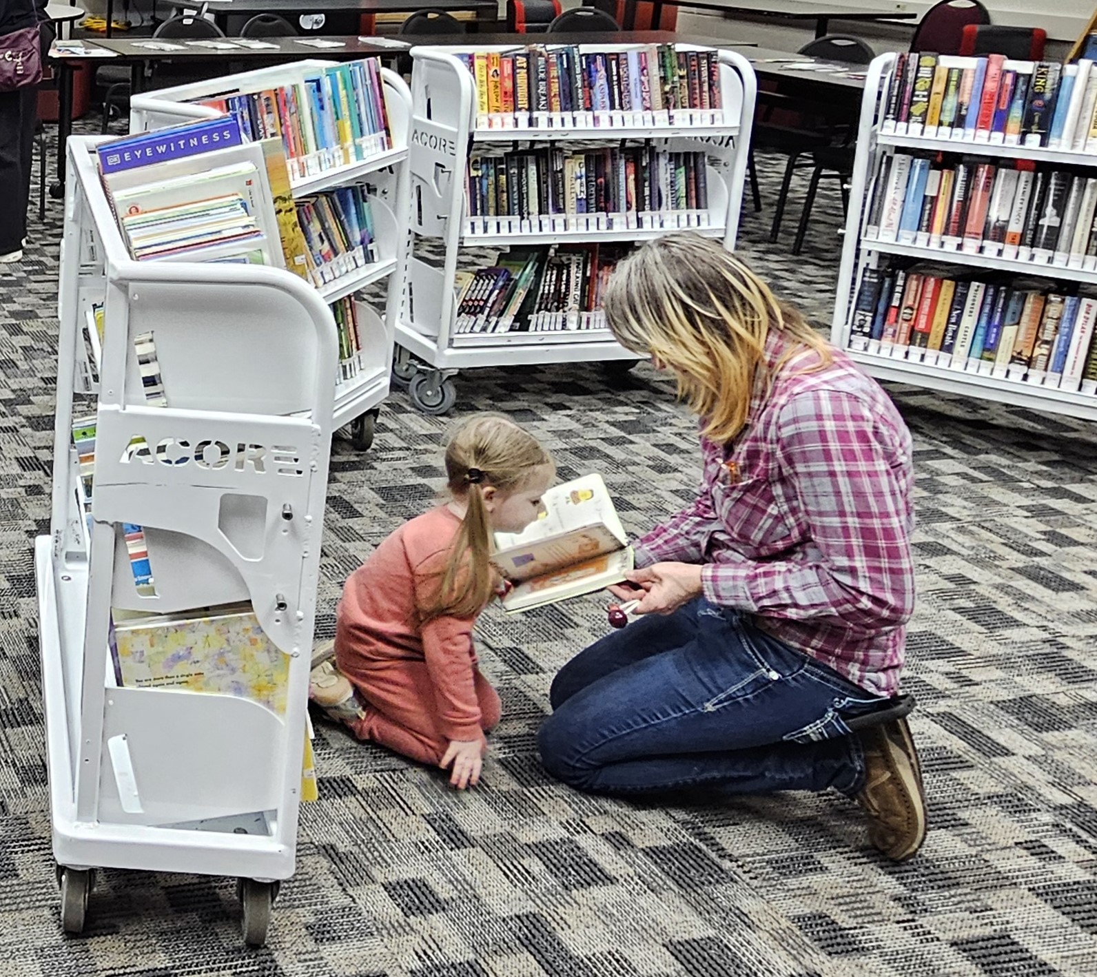 a young learner reading with a parent at the PLOS Bookmobile