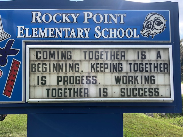 School sign reads: Coming together is a beginning, keeping together is progress. Working together is success.