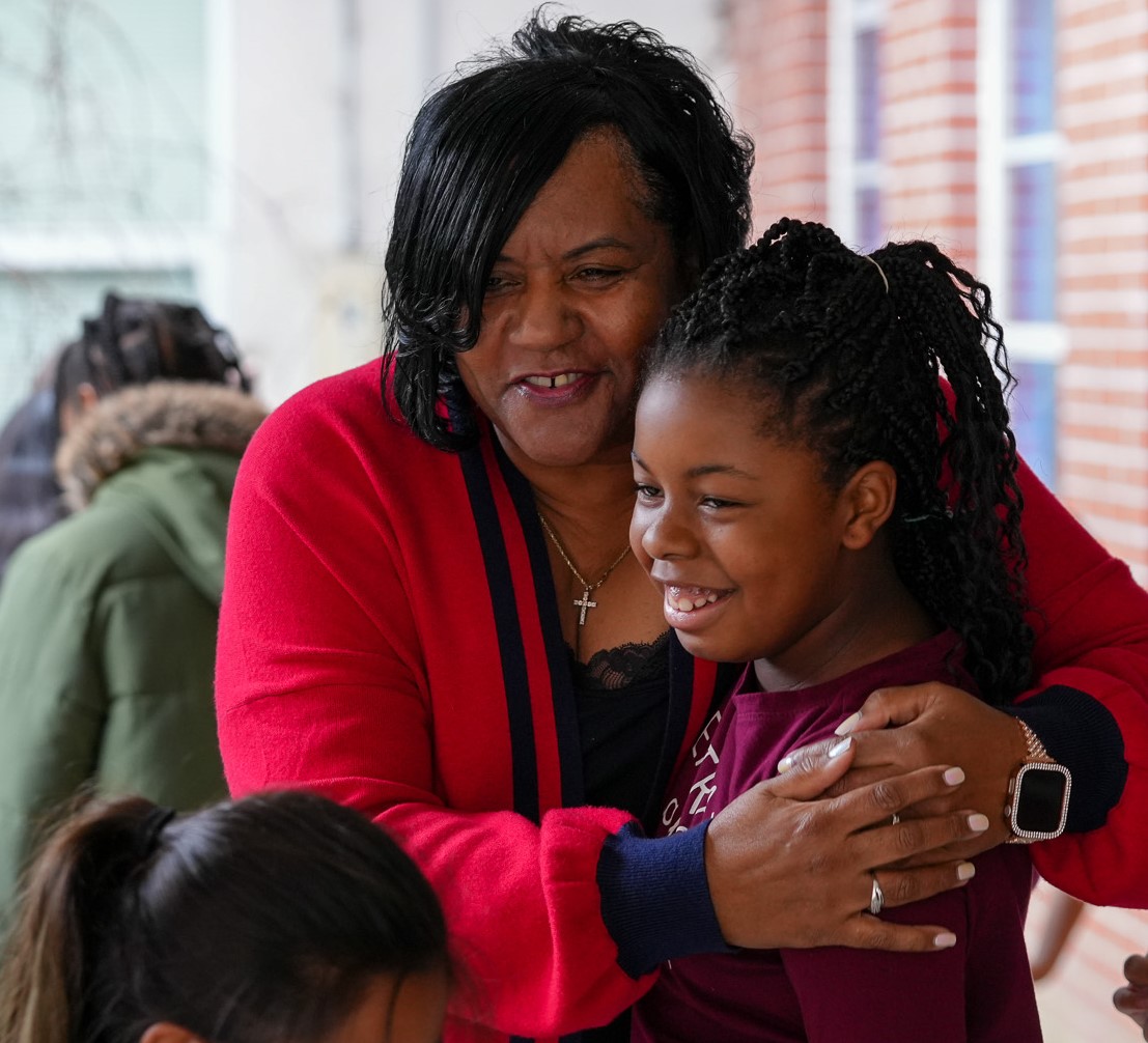 Teacher hugs smiling student