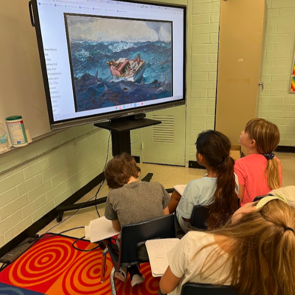 Students sit in chairs facing  a large mobile screen. On the screen is a painting of a man in a boat with sharks in the foreground. 