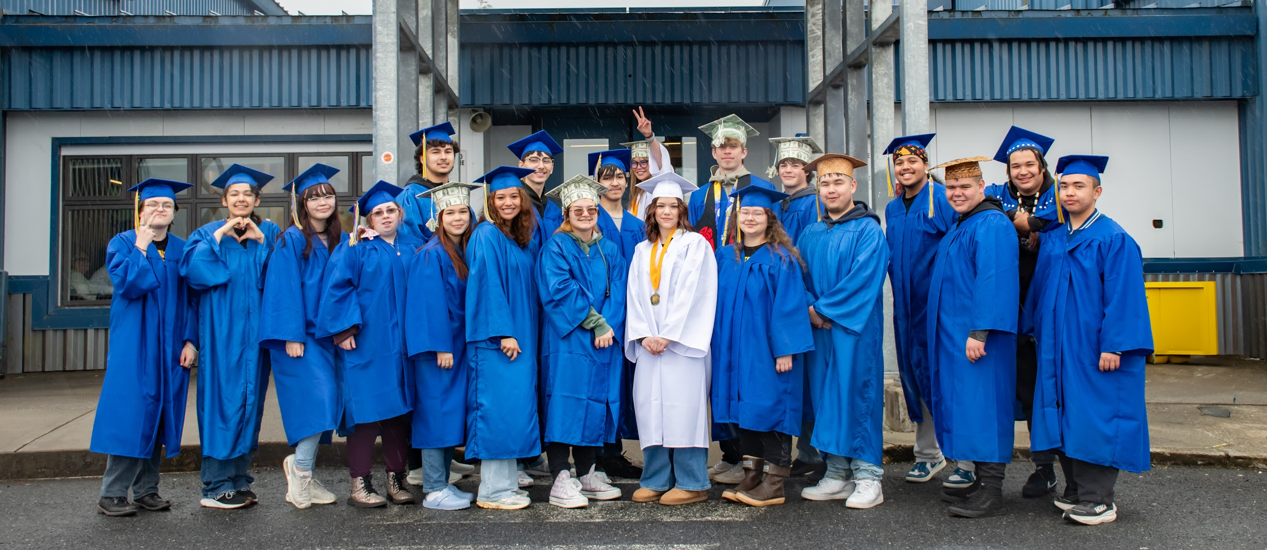 seniors in front of school in caps and gowns