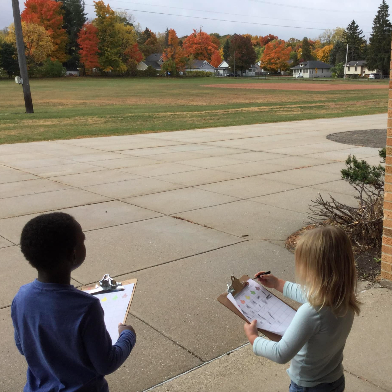 two children using clipboards outdoors