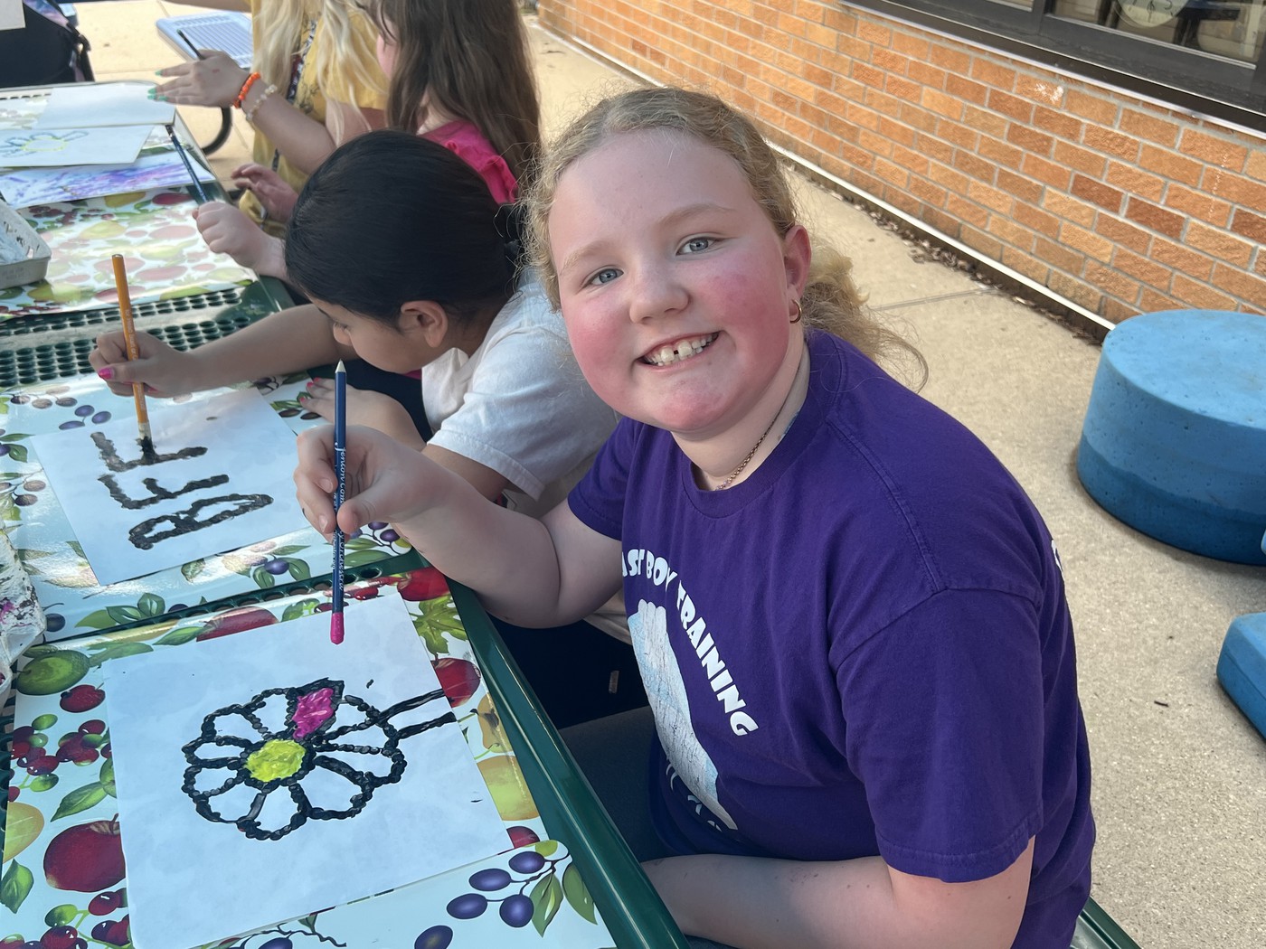 girl smiling and using paint brush with paint on white paper