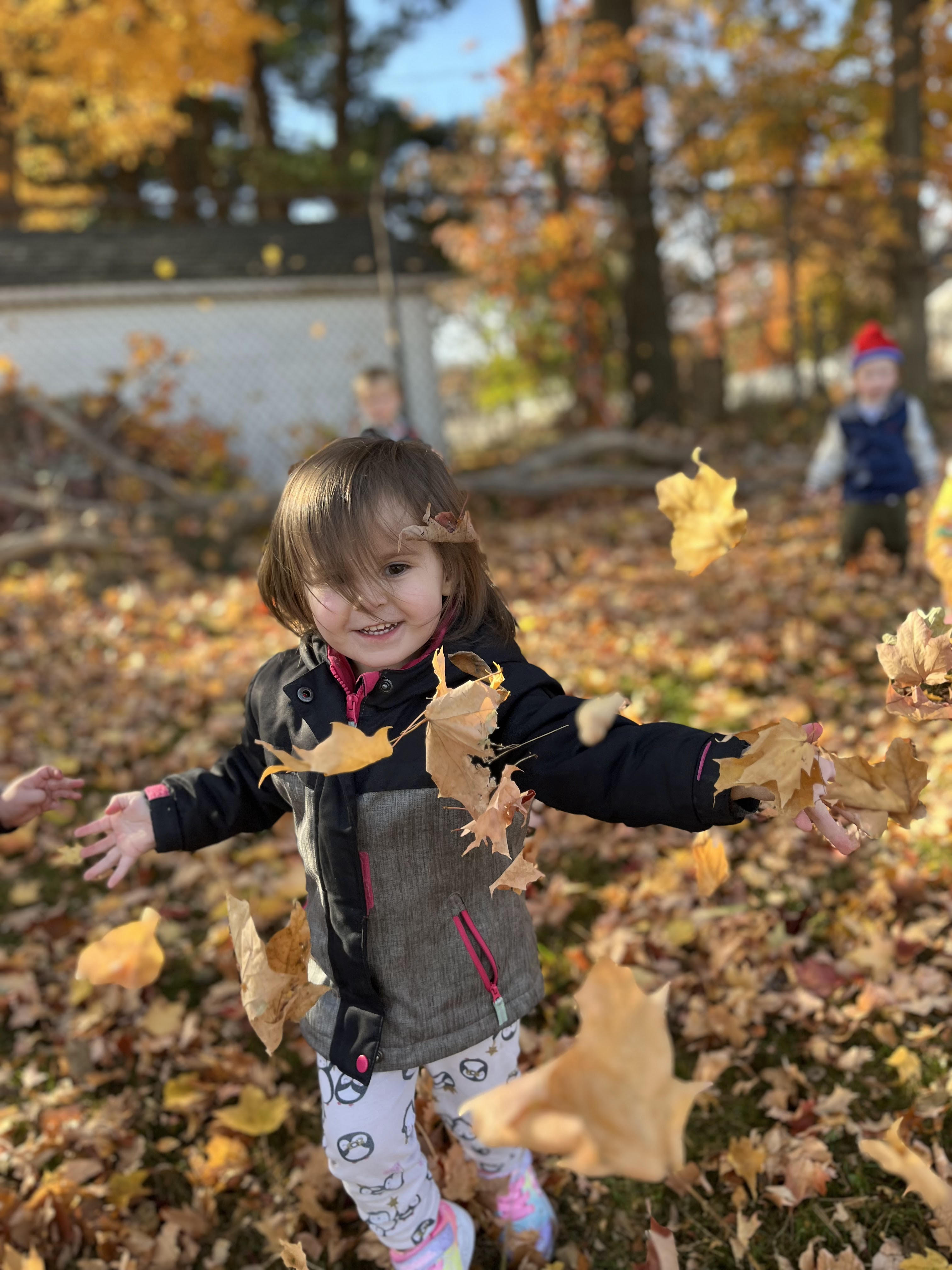 toddler girl throwing leaves in the air