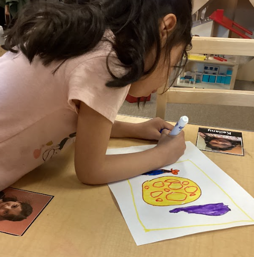 Child draws blue, yellow, and purple images 