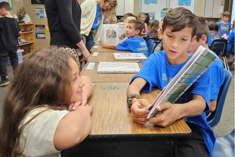 young boy reads to female classmate