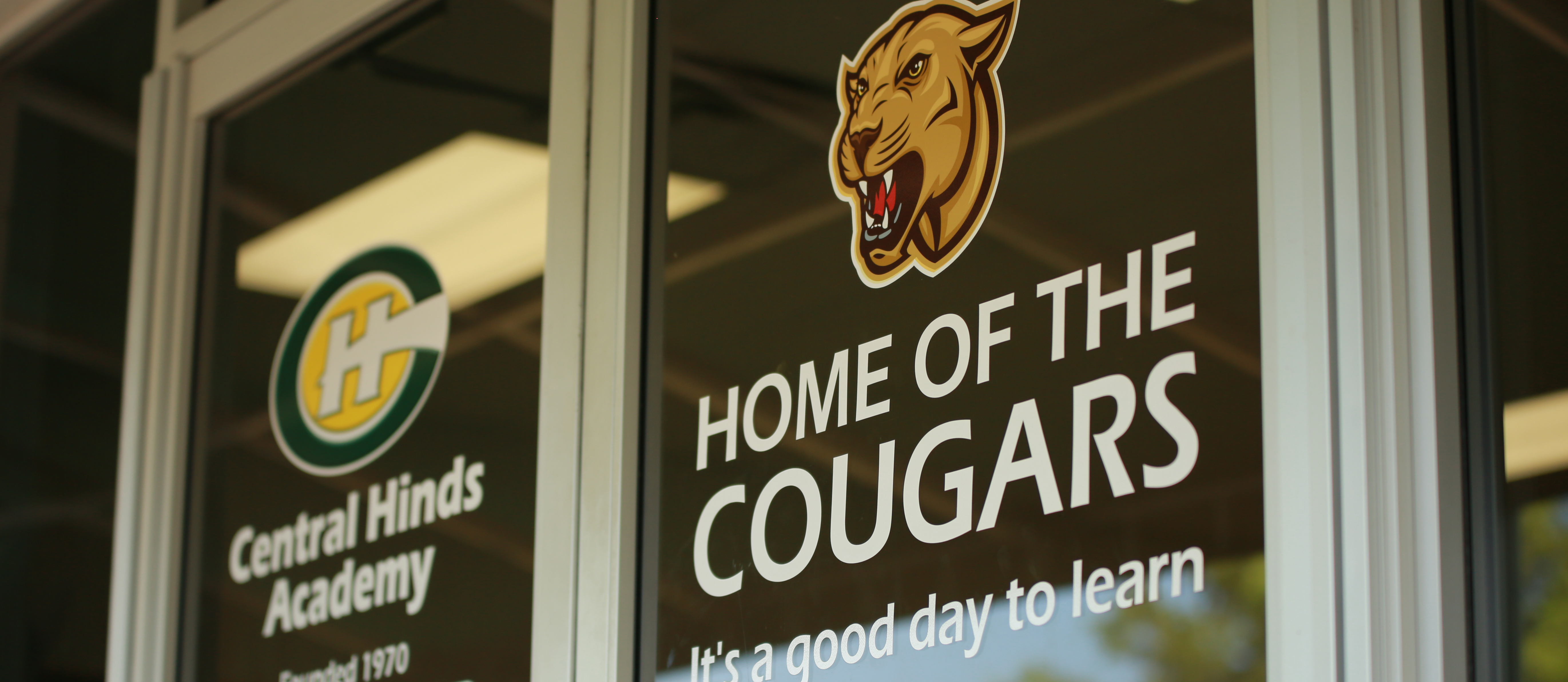 Central Hinds Seniors in sports uniforms standing in front of a school bus. Students are holding a Class of 2022 shirt. 