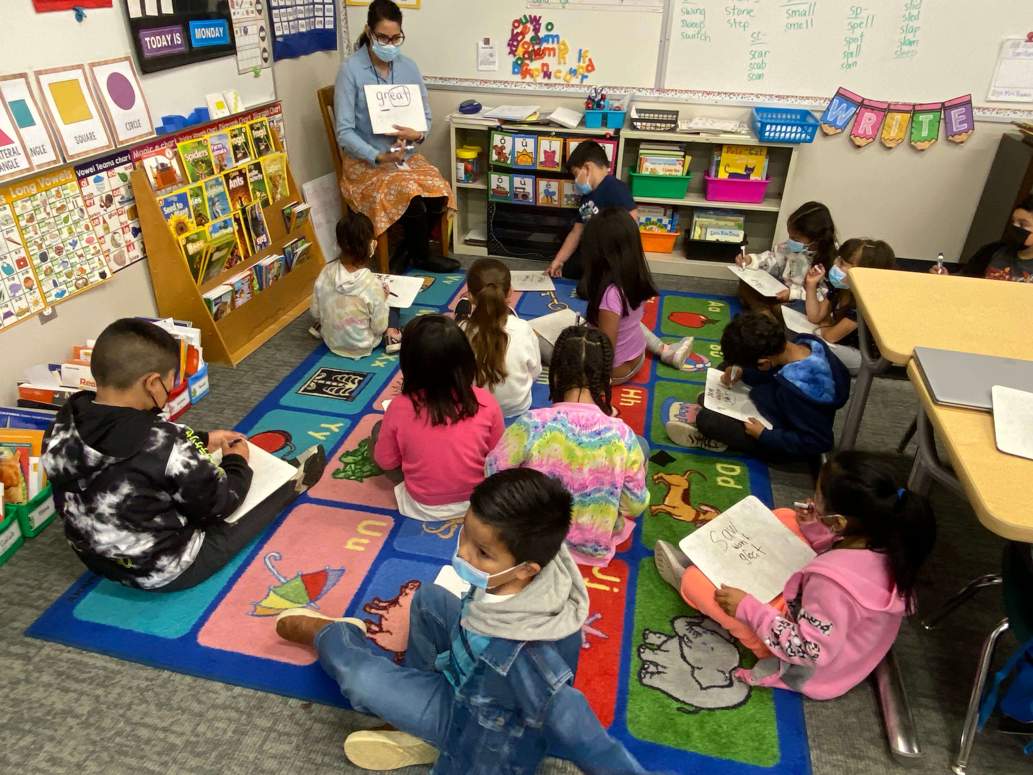 students in classroom on alphabet carpet doing homework